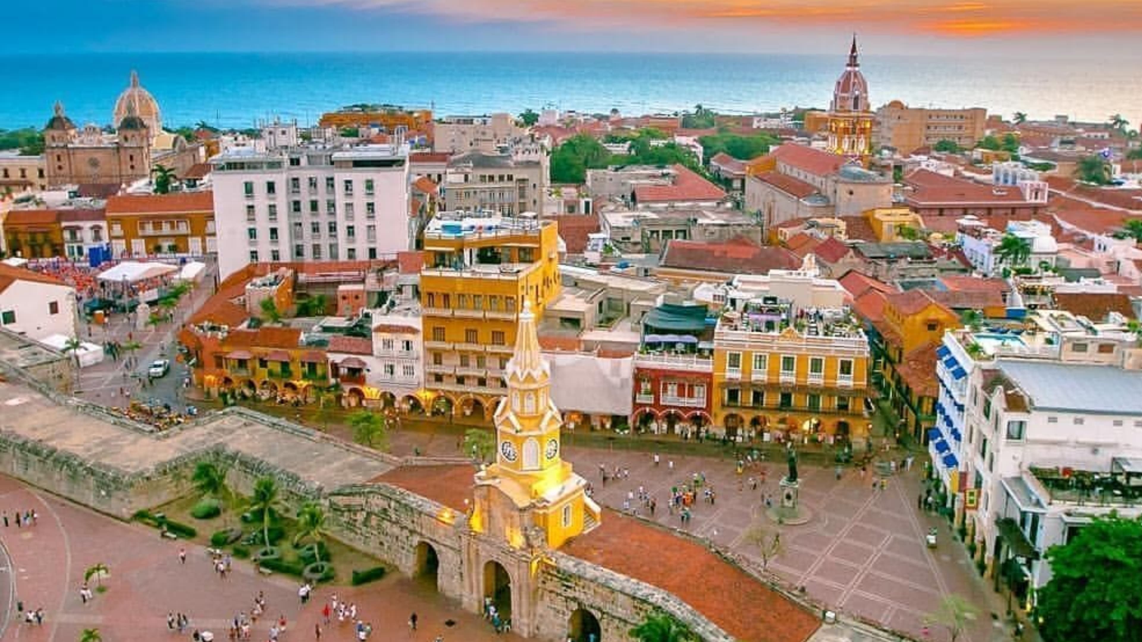 Calle colorida con vendedora de frutas y banderas de Colombia en Cartagena de Indias — paquete desde Chile